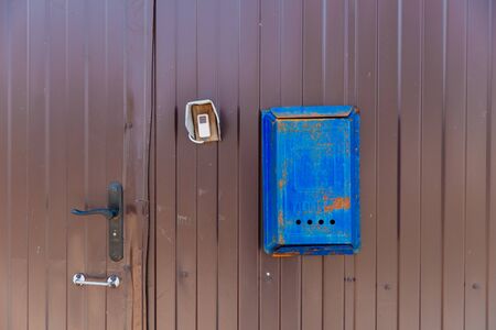 Old blue mailbox hanging on a brown metal fence.の写真素材