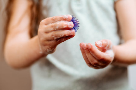 Girl with hands in soap holds an abstract model of coronavirus. Protect yourself, wash your hands.の写真素材