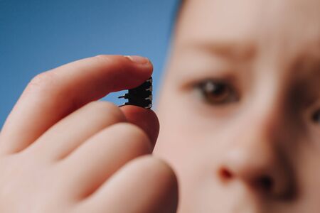 A girl holds in her hand and examines a small black chip. Chipization of people after an epidemic coronavirus.の写真素材