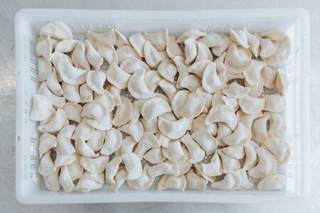 Raw dumplings from the dough in handmade flour lie in a white box.の写真素材
