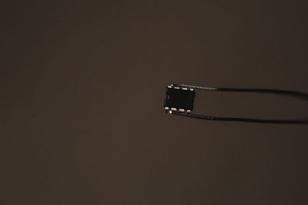 The tweezers hold a small black chip. Chipization of people after an epidemic coronavirus. Copy...