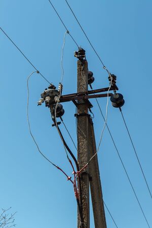  Power line post with electricity cables against a clear sky with white clouds. Electricity transmission line, power supplyの写真素材