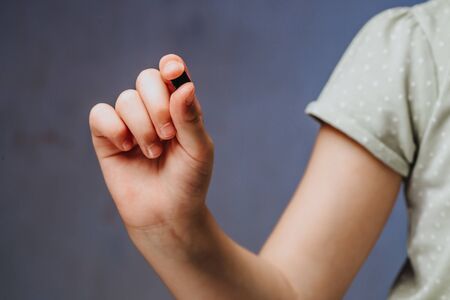 A girl holds in her hand and examines a small black chip. Chipization of people after an epidemic coronavirus.の写真素材