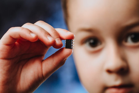 A girl holds in her hand and examines a small black chip. Chipization of people after an epidemic...