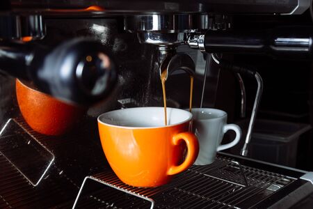 Freshly brewed coffee is poured from the coffee machine into cups . Pouring, beverage.の写真素材