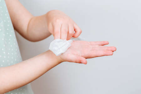 The child wipes her hands wet antibacterial wipe. The concept of hand cleanliness and the fight against virus microbes.の写真素材