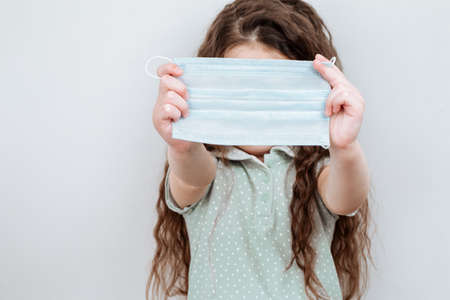 A girl holds a medical masks in her hands. Prevention of infection and dissemination of coronavirus, quarantine.の写真素材