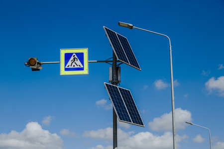 The pedestrian crossing sign powered by solar panels installed above. Traffic signs and rules. Against the background of a blue sky with cloudsの写真素材