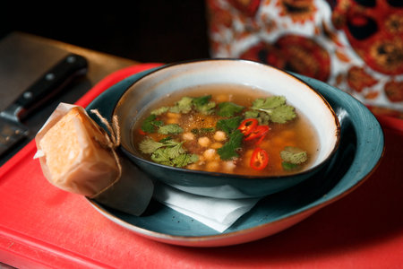 Freshly made aromatic chickpea and meat soup topped with parsley. Served with bread wrapped in...