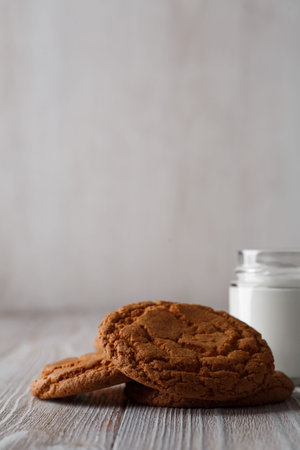 Tasty cookies and a glass of milk in a transparent glass on a rustic white background. Copy space
