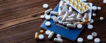 A pills, passport on a wooden background. The concept of self-isolation during the coronavirus COVID-19 pandemicの写真素材
