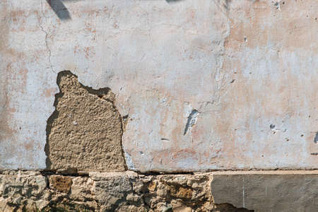 Plaster peeling off brick wall. The foundation of a residential building is gradually collapsing.の写真素材