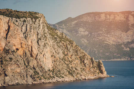 Colorful landscape with blue sea, mountain and sky with sun in the evening.の写真素材