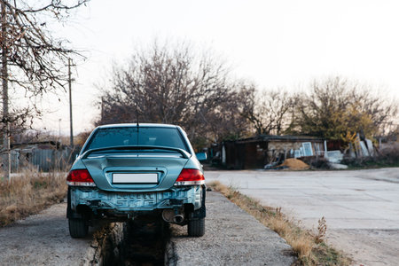 A car without a bumper, the exhaust pipe is visible. The trunk lid is dented. Auto after accident. Repair is needed. Car insurance conceptの写真素材