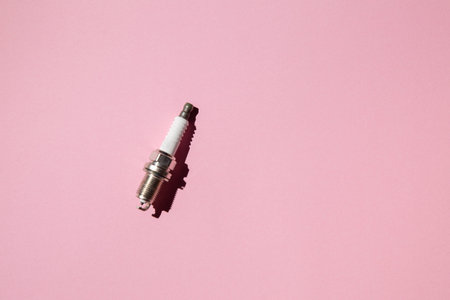 Spark plug. Car candle lies against a pink background. Auto engine electrician. Flat lay. Copy space
