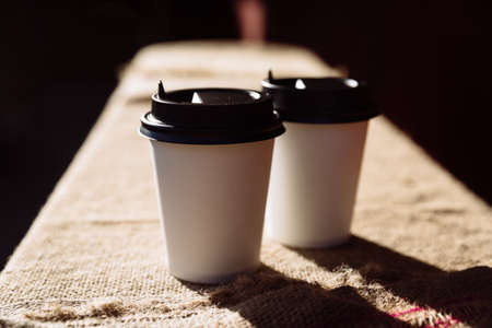 Two paper coffee cups pound on burlap. Takeaway cup of coffee beansの写真素材
