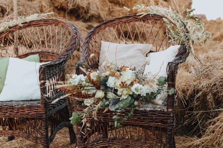 Two wicker chairs with white cushions and a bouquet of flowers on it. Boho styleの写真素材