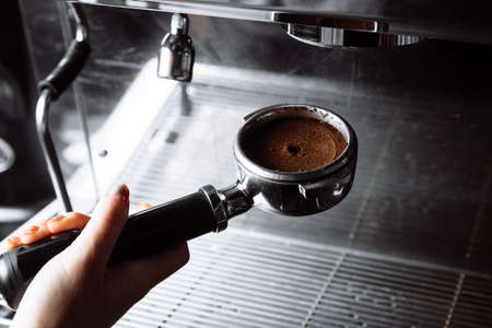 Barista pressing ground coffee into portafilter by tamper.の写真素材