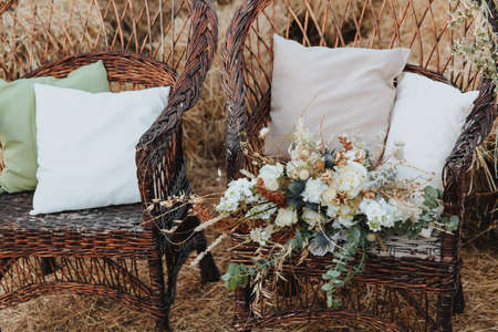 Two wicker chairs with cushions and a bouquet of flowers on it. Boho styleの写真素材