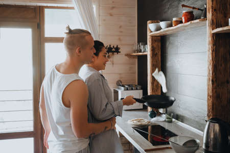 Loving couple preparing food together enjoying cooking while standing in kitchen.の写真素材