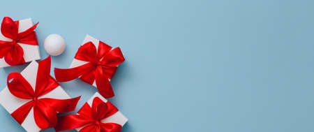 Present boxes on blue background greeting card holidays concept, gift white box tied with red ribbon, holiday bannerの写真素材