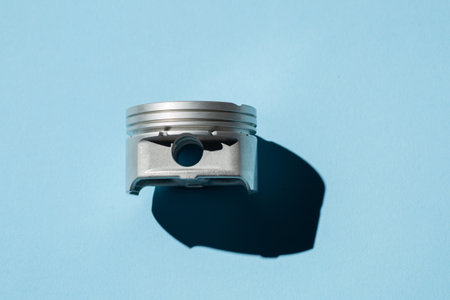 Piston from a car engine on the blue background with copy space. Machinery abstract background.の写真素材