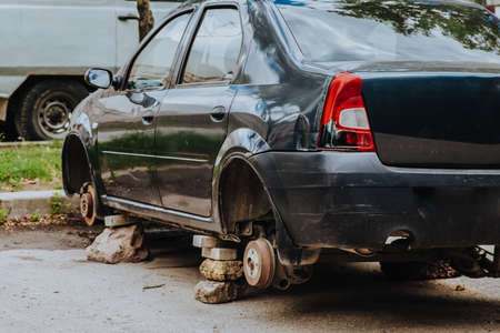 A broken passenger car without wheels stands on bricksの写真素材