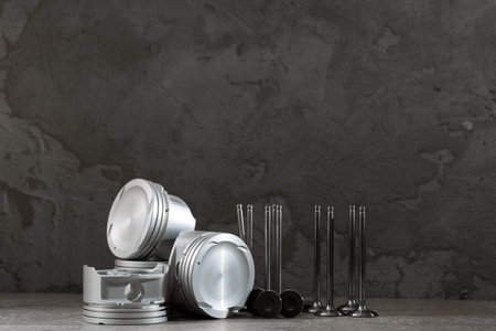 Set of new car pistons and valves on concrete gray background, car repair parts