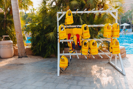 Stack of hanging yellow life vests on hangers outside during the marine activities, safety clothing, protection conceptの写真素材