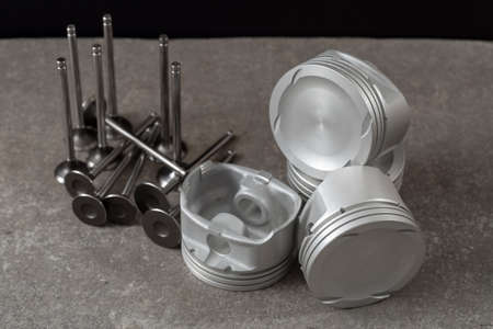 Set of new car pistons and valves on concrete gray background, car repair partsの写真素材