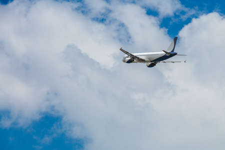 White- blue passenger airplane flying in the sky amazing clouds in the backgroundの写真素材