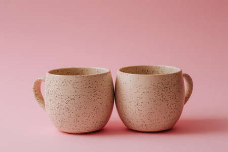 Two ceramic cups stand on a pink background, copy spaceの写真素材