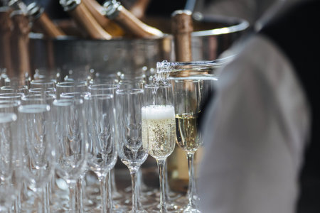 Waiter pouring champagne in stylish glasses at luxury reception, celebration.
