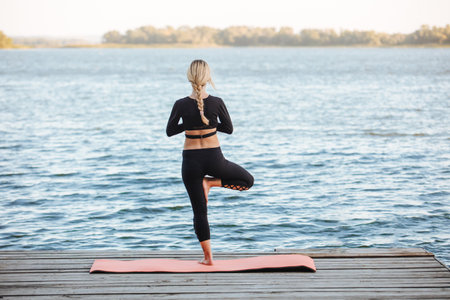 woman do yoga and meditate near water on bridge in nature.の写真素材