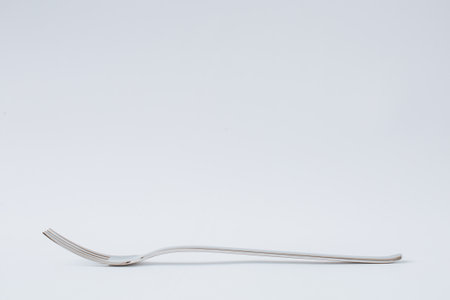 Stainless steel fork for eating on white background, kitchenware, copy space, close-upの写真素材