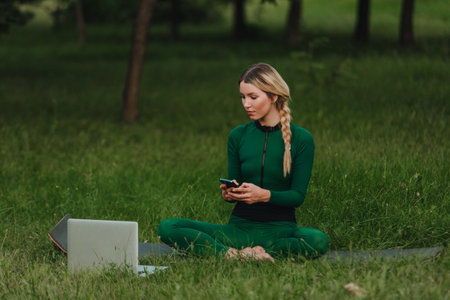 Yoga classes on the grass in the park using a mobile phone.の写真素材