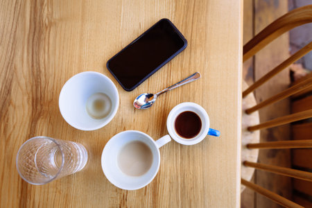 Dirty coffee cups, cappuccino and a glass of water stand on a wooden table.の写真素材