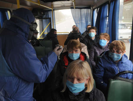 A medical professional conducts a temperature examination at a checkpoint at the entrance to Kiev, April 16, 2020.のeditorial素材