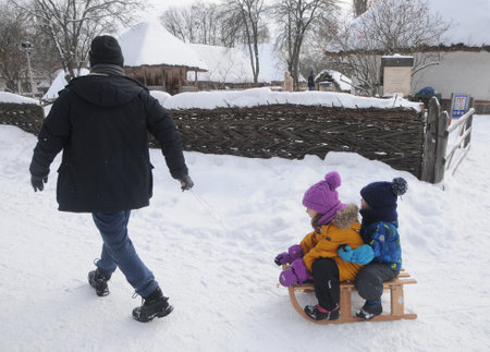 A man carries children on a sled during Christmas celebrations at the National Museum of Folk Architecture and Life in Kiev, January 7, 2019.のeditorial素材
