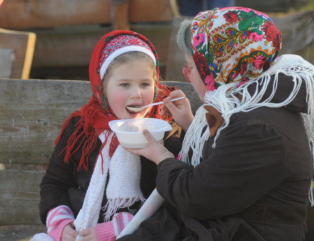 A woman feeds a girl with kutya during an ethnographic entertainment program at the National Museum of Folk Architecture and Life of Ukraine in Pirogovo, January 12, 2020.のeditorial素材