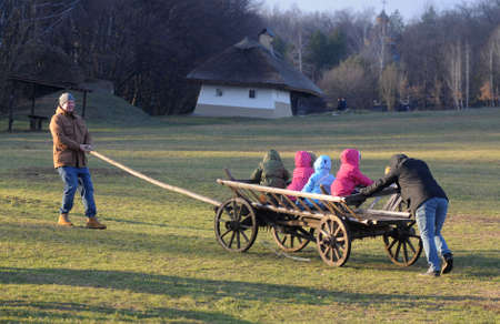 Men ride children on a cart during an ethnographic entertainment program. National Museum of Folk Architecture and Life of Ukraine in Pirogovo, January 12, 2020のeditorial素材