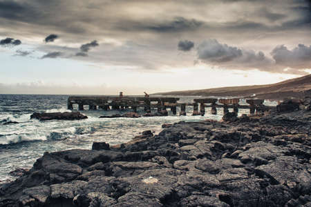 old bridge rack on an ocean lava beach in Hawaii during sunsetの写真素材