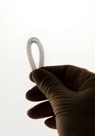 surgeon's hand holding self-expanding braided nitinol stent for endovascular surgeryの写真素材