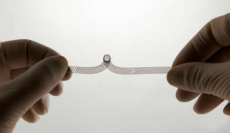 surgeon's hand twisting self-expanding braided nitinol stent for endovascular surgeryの写真素材