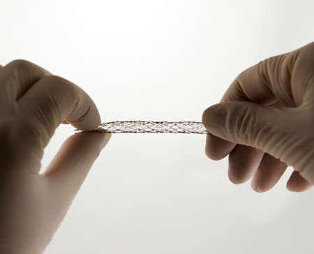 surgeon's hands twisting self-expanding meshed nitinol stent for endovascular surgeryの写真素材