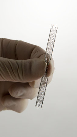 surgeon's hand compressing self-expanding meshed nitinol stent for endovascular surgery