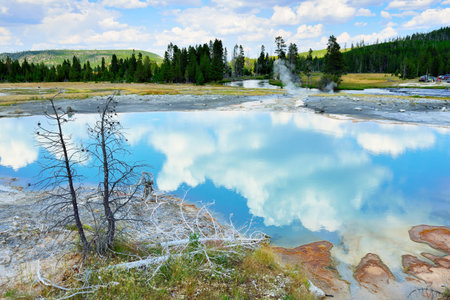 Clouds reflecting in the Sapphire pool in Biscuit Basin in Yellowstone National Park in Summerの写真素材