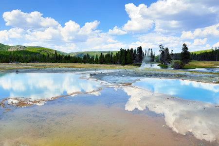 Clouds reflecting in the Sapphire pool in Biscuit Basin in Yellowstone National Park in Summerの写真素材