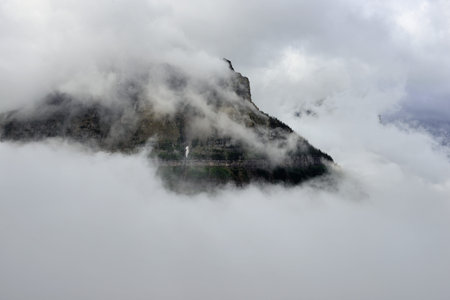 high and steep mountain surrounded by heavy clouds in Glacier National Park