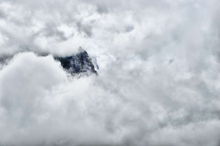 high and steep mountain surrounded by heavy clouds in Glacier National Parkの写真素材